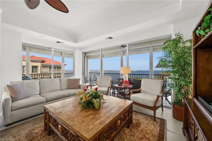 Another photo featuring the water views, tray ceiling, elegant furniture and ceiling fan