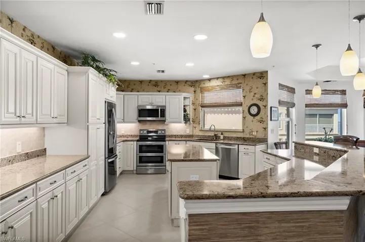 Completely remodeled kitchen featuring an extra large island with a wealth of additional cabinets, granite counters, stainless steel appliances, pendant lighting and an amazing amount of storage!
