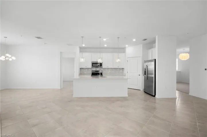 Kitchen with a chandelier, appliances with stainless steel finishes, white cabinets, open floor plan, and recessed lighting