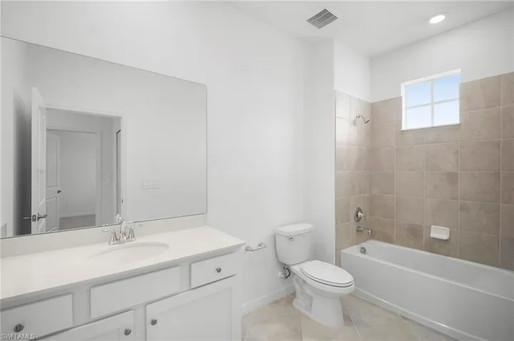 Bathroom featuring shower / bathtub combination, vanity, and light tile patterned floors