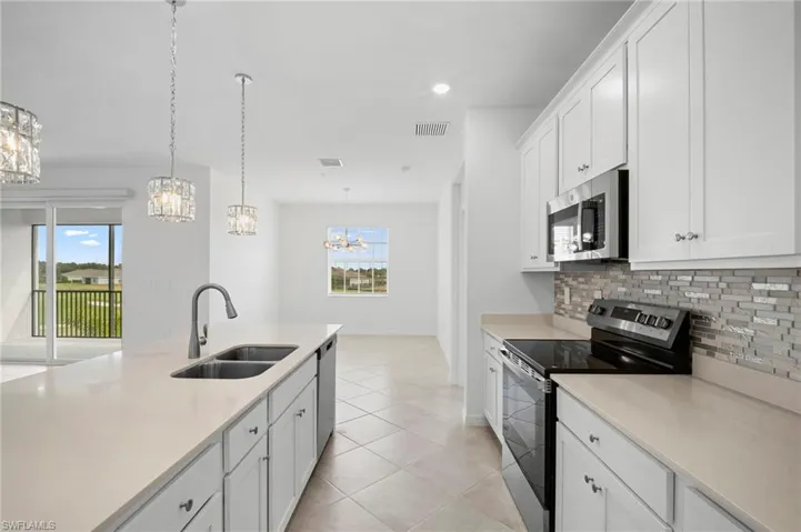 Kitchen with appliances with stainless steel finishes, white cabinetry, pendant lighting, tasteful backsplash, and light tile patterned floors