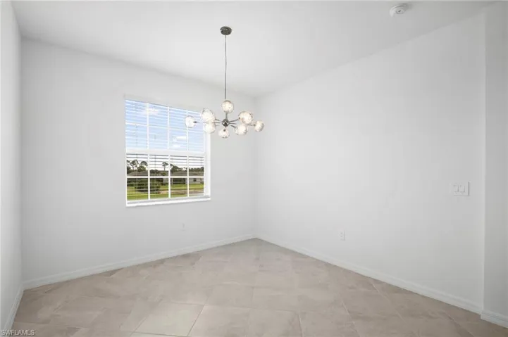 Unfurnished room featuring a chandelier and baseboards