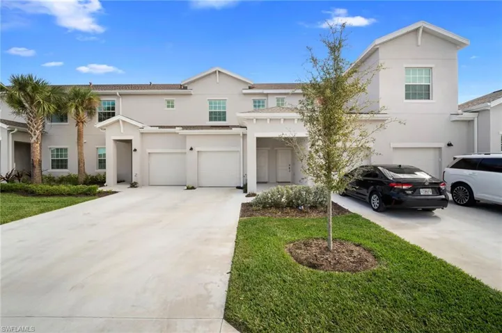 Traditional-style home featuring stucco siding, an attached garage, driveway, and a front yard