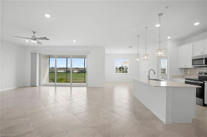 Kitchen with appliances with stainless steel finishes, white cabinetry, pendant lighting, open floor plan, and backsplash