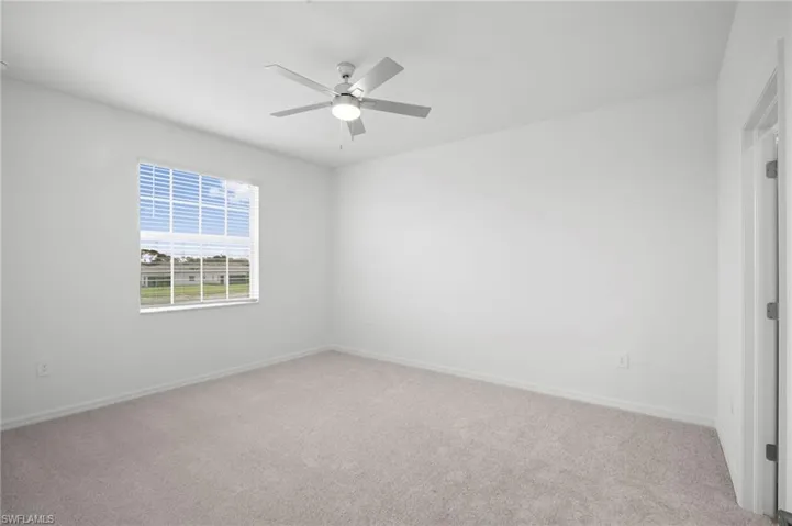 Spare room featuring light colored carpet and a ceiling fan