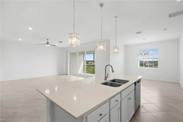 Kitchen with an island with sink, open floor plan, a chandelier, hanging light fixtures, and recessed lighting