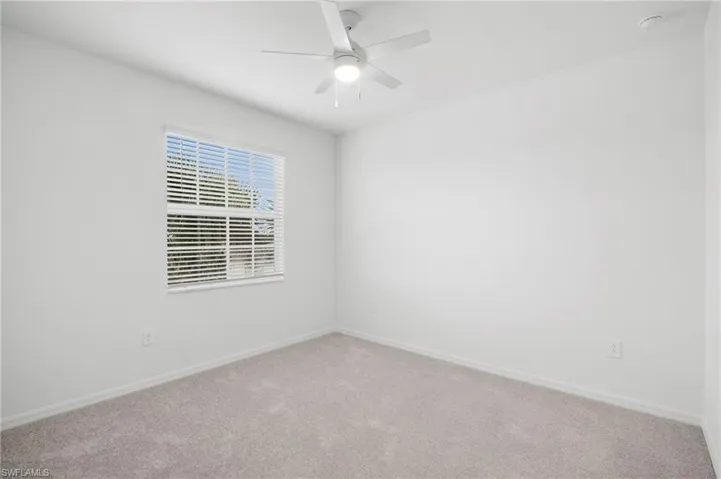 Empty room featuring carpet flooring and a ceiling fan