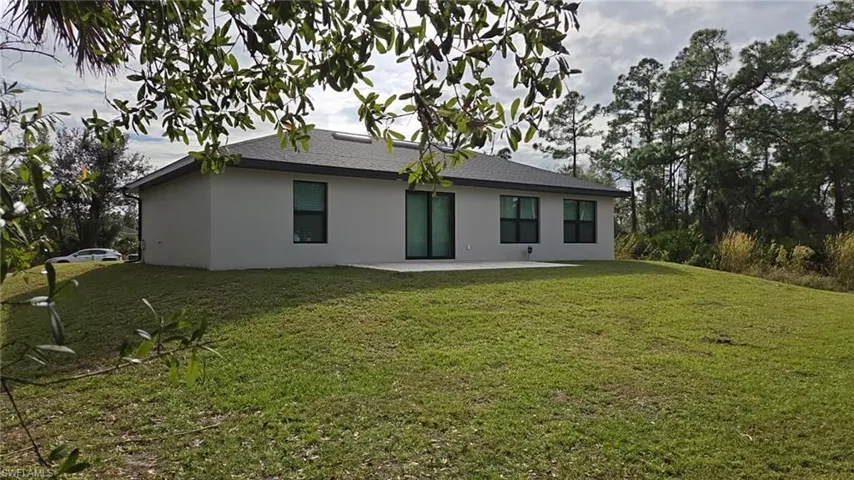 Rear view of property with a patio, a yard, stucco siding, and a shingled roof