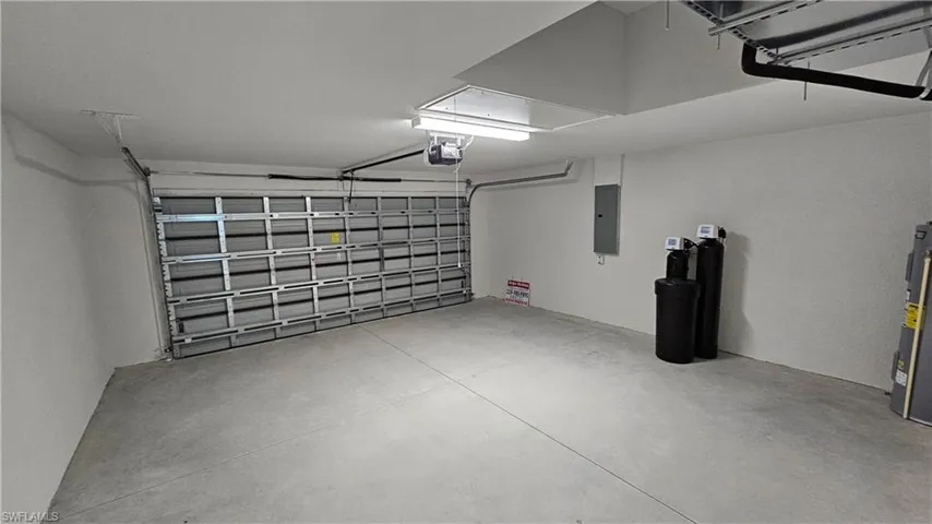 Garage with electric panel, water heater, and a garage door opener