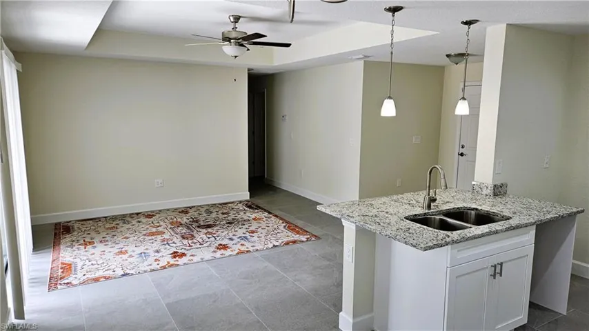Kitchen featuring a sink, a ceiling fan, baseboards, decorative light fixtures, and white cabinetry