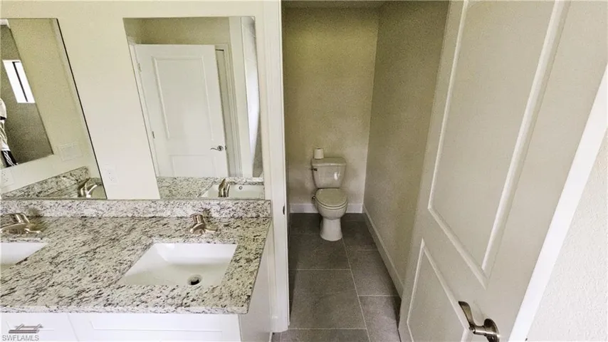 Full bathroom featuring tile patterned floors, toilet, and double vanity
