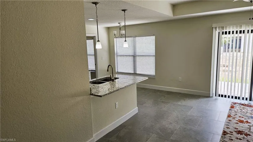 Kitchen with a sink, baseboards, healthy amount of natural light, hanging light fixtures, and a textured wall