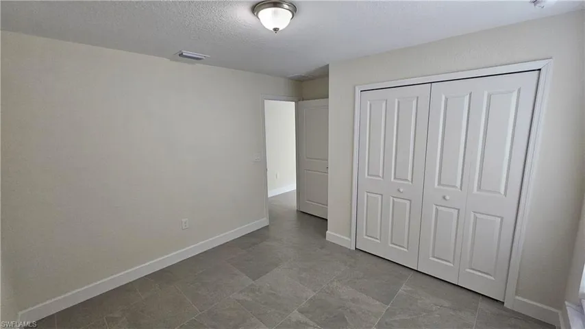 Unfurnished bedroom featuring a textured ceiling, a closet, and baseboards
