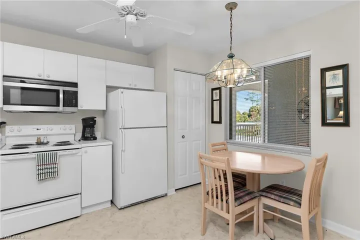 Kitchen featuring white appliances, white cabinetry, a ceiling fan, light countertops, and light floors