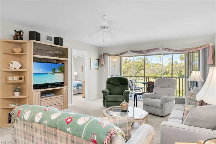 Living room with light colored carpet, a ceiling fan, and a sunroom