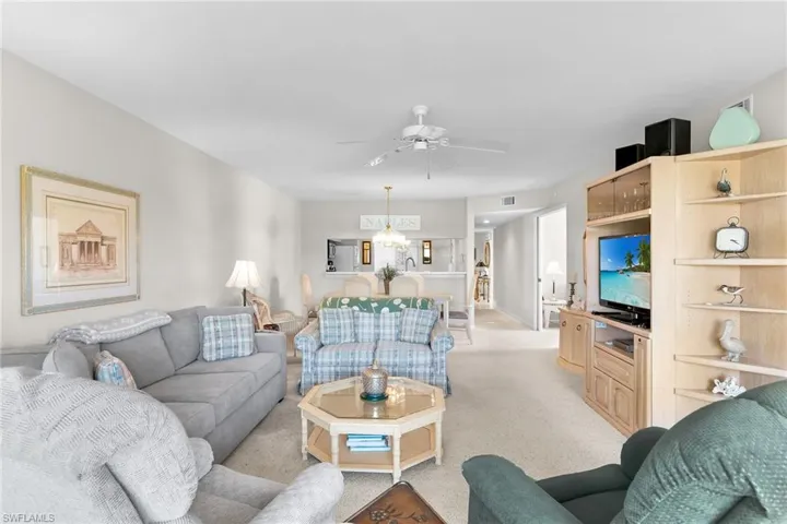 Living area with light colored carpet, ceiling fan, and a chandelier