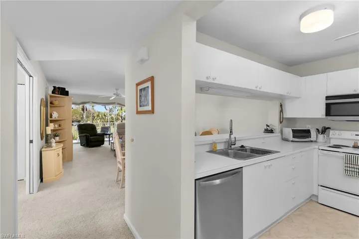 Kitchen featuring stainless steel appliances, light countertops, white cabinets, and light carpet