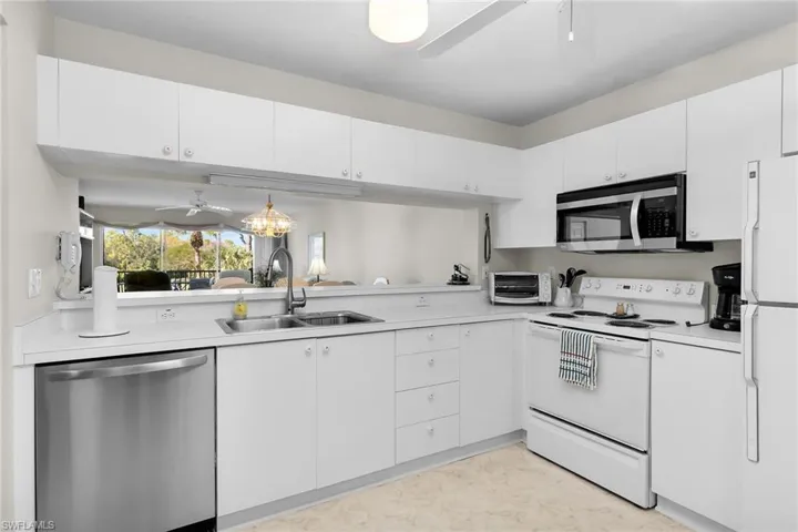 Kitchen featuring ceiling fan, stainless steel appliances, white cabinetry, and light countertops