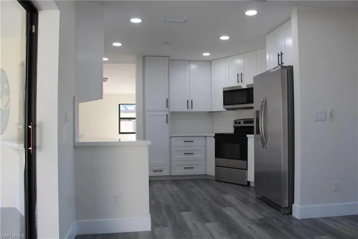 Kitchen featuring white cabinetry, dark hardwood / wood-style flooring, and appliances with stainless steel finishes