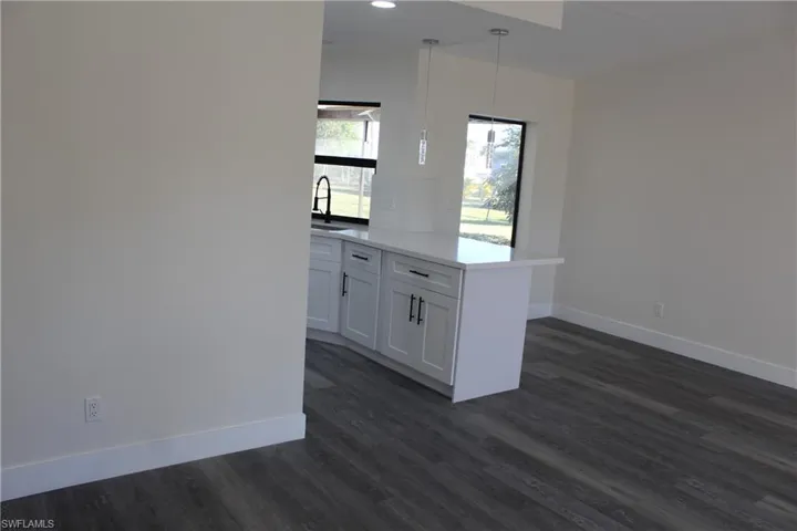 Kitchen with kitchen peninsula, pendant lighting, dark hardwood / wood-style flooring, and white cabinetry