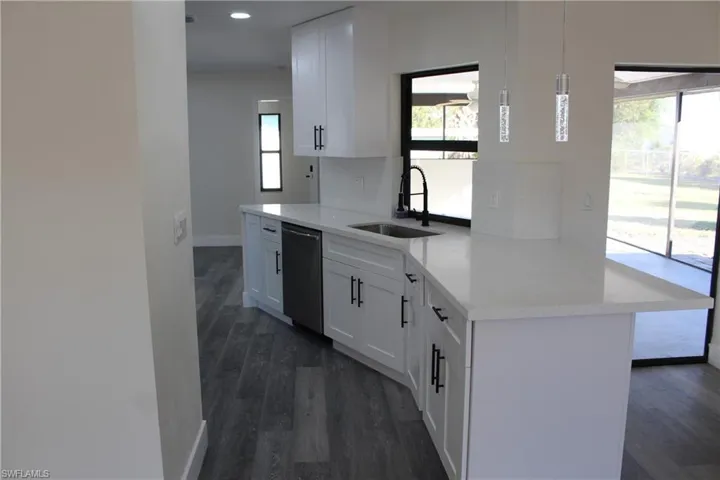 Kitchen with kitchen peninsula, pendant lighting, dishwasher, white cabinets, and dark hardwood / wood-style floors