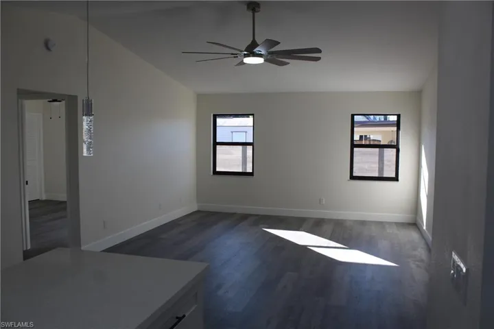 Unfurnished room featuring ceiling fan, dark wood-type flooring, and lofted ceiling