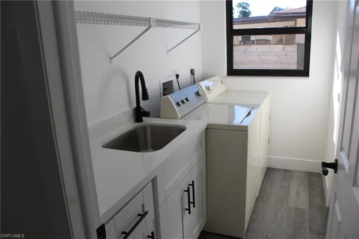 Washroom with washer and clothes dryer, cabinets, sink, and light hardwood / wood-style flooring