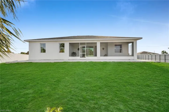 Back of house featuring stucco siding, fence, a lawn, and a sunroom