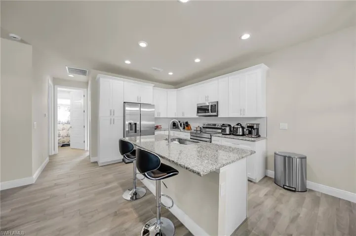 Kitchen featuring a sink, visible vents, light wood-style flooring, baseboards, and appliances with stainless steel finishes