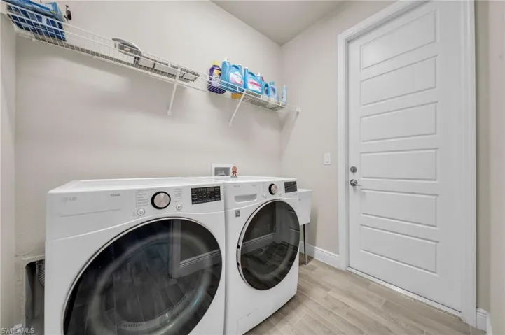 Laundry area featuring washer and dryer, baseboards, laundry area, and light wood-type flooring