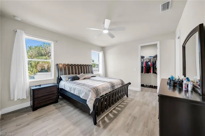 Bedroom with visible vents, baseboards, a spacious closet, and light wood-style floors
