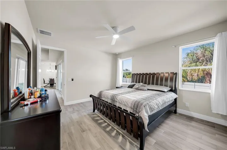 Bedroom with baseboards, visible vents, ceiling fan, and light wood finished floors