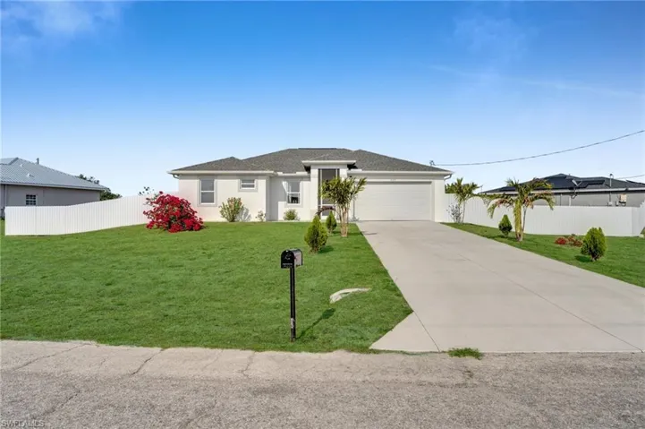 Prairie-style home featuring a front lawn, driveway, an attached garage, and fence
