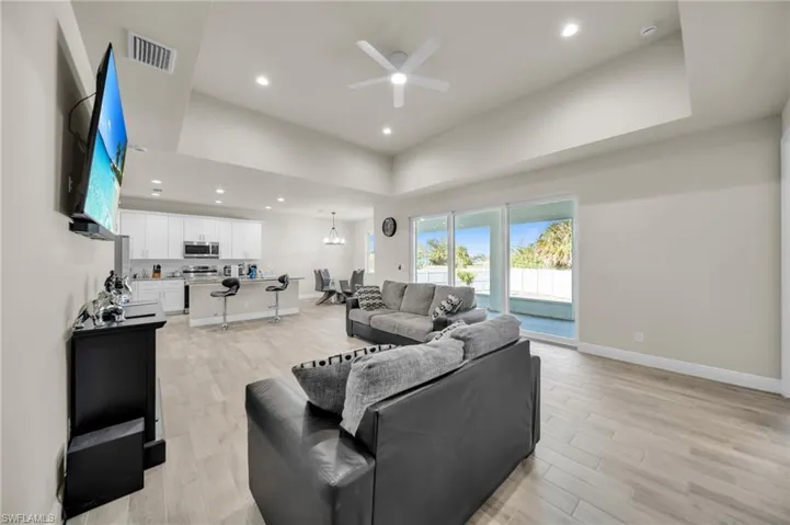 Living room featuring recessed lighting, light wood-style flooring, ceiling fan, baseboards, and visible vents