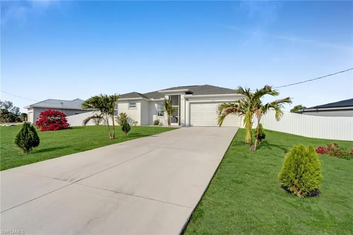 Prairie-style house with stucco siding, fence, a garage, driveway, and a front lawn