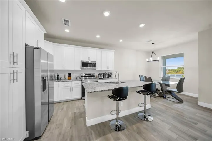 Kitchen featuring baseboards, light wood-type flooring, stainless steel appliances, and a sink