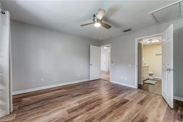 Unfurnished bedroom with wood-type flooring, ensuite bath, and ceiling fan