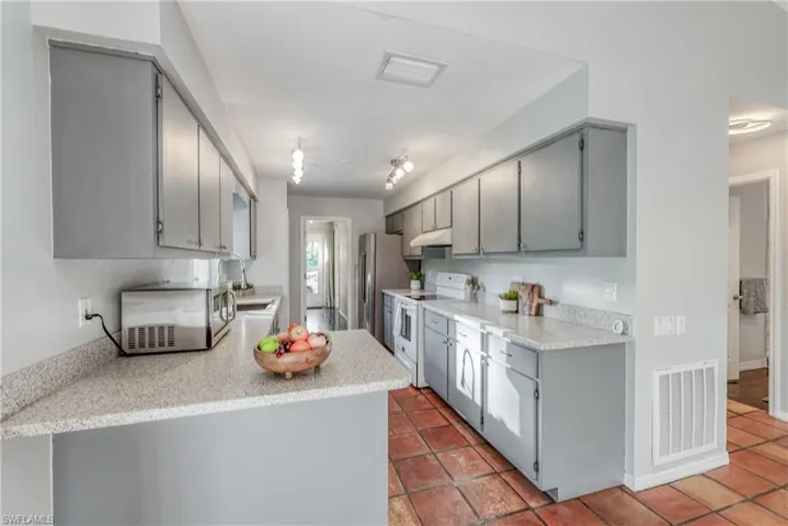 Kitchen featuring appliances with stainless steel finishes, light tile patterned flooring, sink, and gray cabinetry