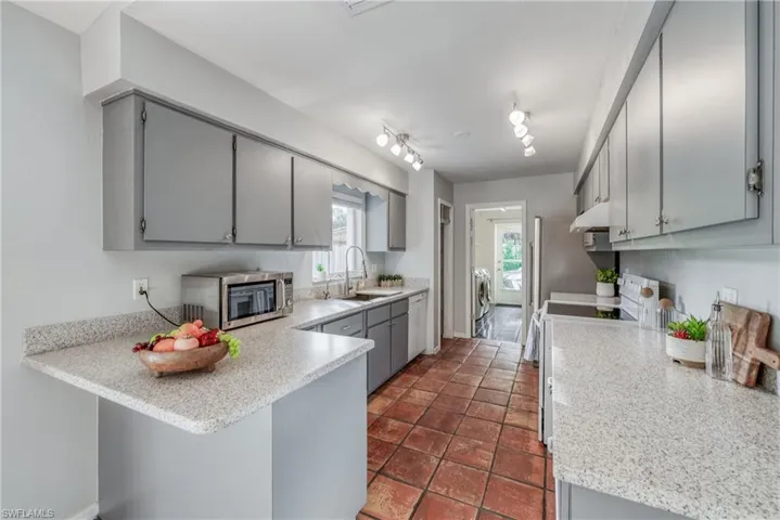 Kitchen featuring separate washer and dryer, rail lighting, electric range oven, kitchen peninsula, and sink