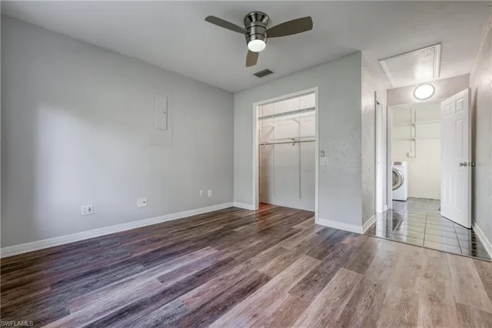 Unfurnished bedroom with a walk in closet, a closet, hardwood / wood-style floors, washer / clothes dryer, and ceiling fan