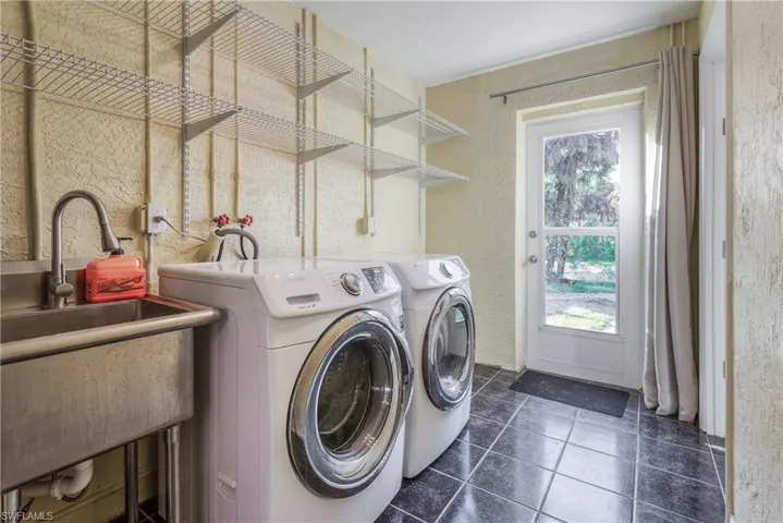 Washroom featuring washing machine and dryer, sink, and dark tile patterned flooring