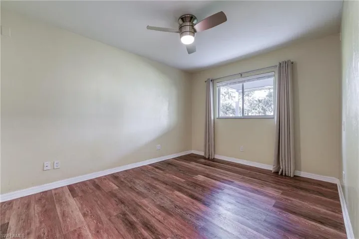 Unfurnished room featuring ceiling fan and dark hardwood / wood-style floors