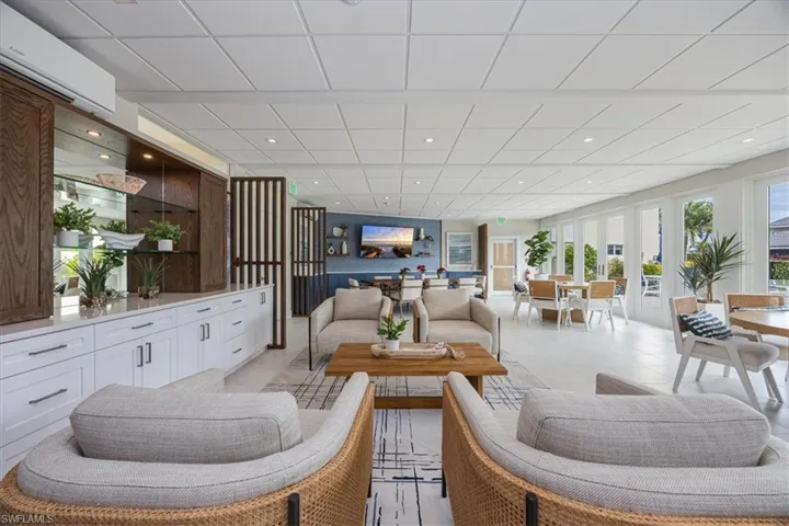 Living room featuring an AC wall unit, light tile patterned flooring, a drop ceiling, and recessed lighting