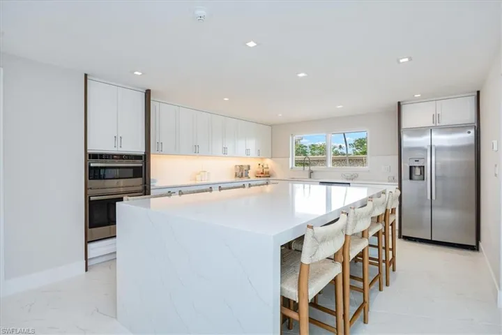 Kitchen featuring a kitchen breakfast bar, stainless steel appliances, white cabinetry, recessed lighting, and a center island