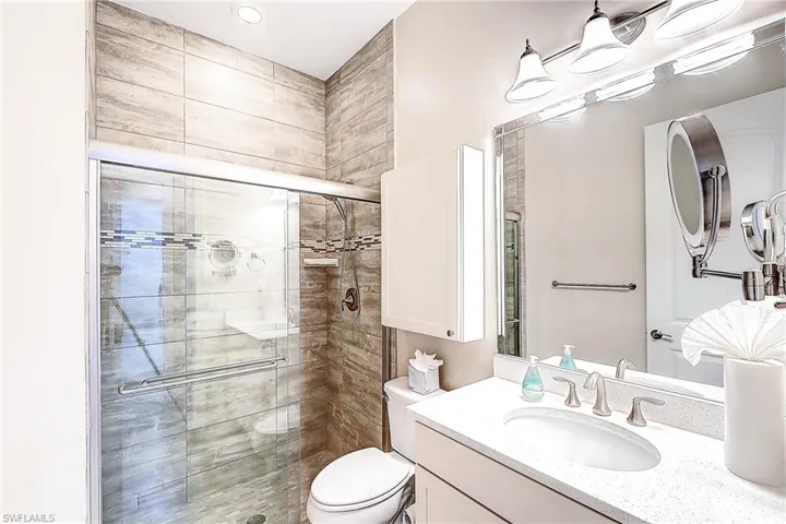 Bathroom featuring a shower with shower door, toilet, and vanity