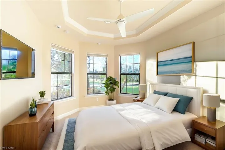 Bedroom featuring carpet, ceiling fan, a raised ceiling, and multiple windows