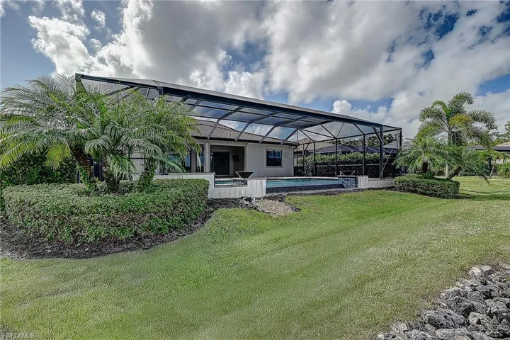 Rear view of house with a lawn and a lanai