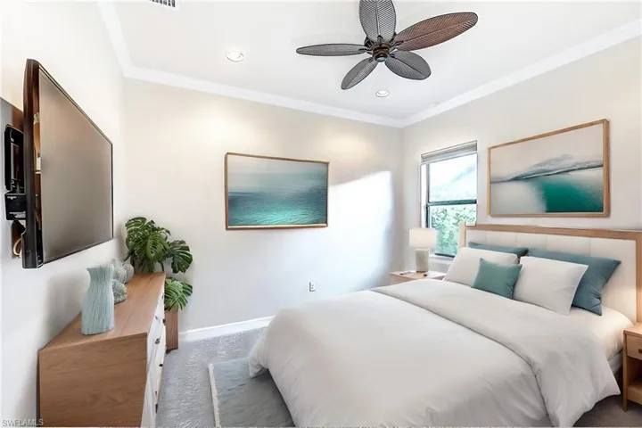 Carpeted bedroom featuring ceiling fan and ornamental molding