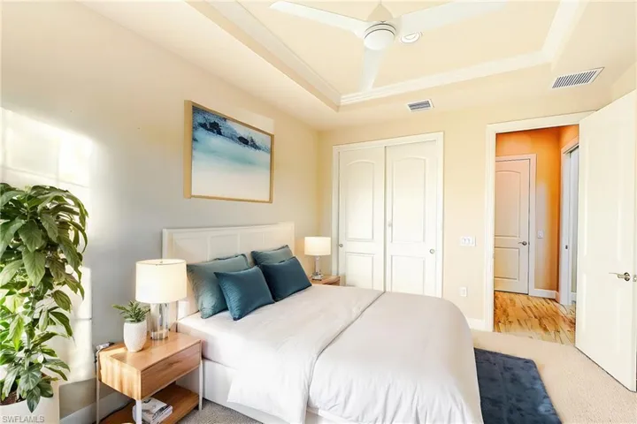 Bedroom with a tray ceiling, ceiling fan, a closet, and light hardwood / wood-style floors