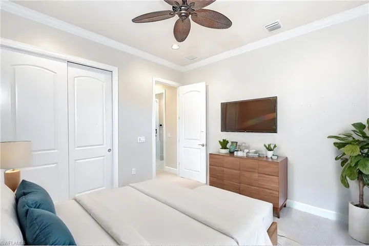 Carpeted bedroom featuring ornamental molding, ceiling fan, and a closet
